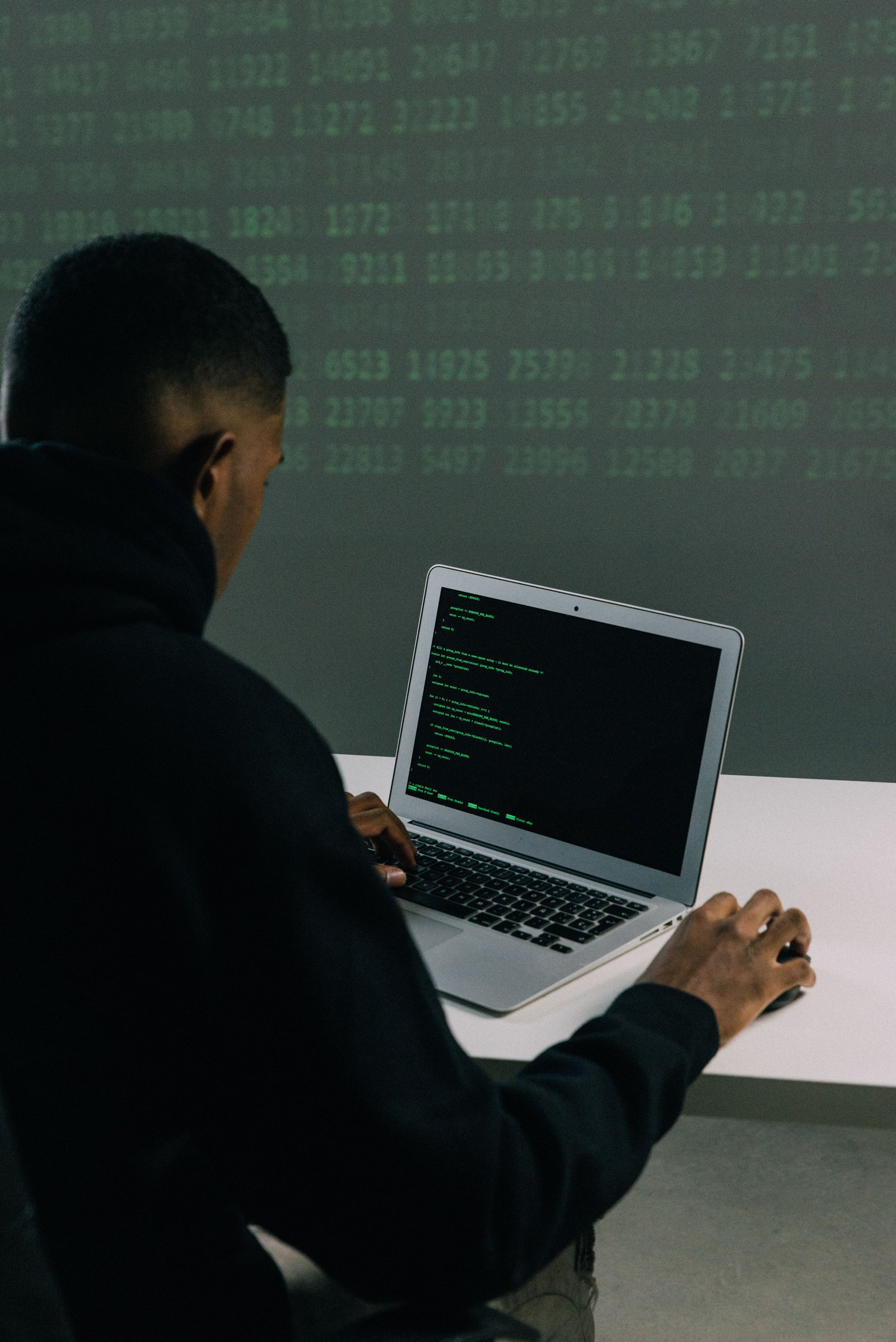 Black developer focused on writing code while working on a laptop